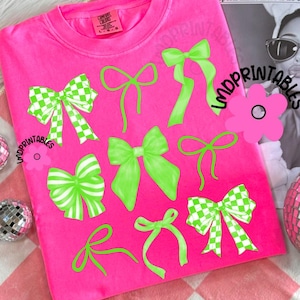 May include: A bright pink Comfort Colors sweatshirt featuring various green bows. Some bows have a checkered pattern, while others are solid. The text "IMDPRINTABLES" is visible on the shirt. A magazine clipping is in the background.