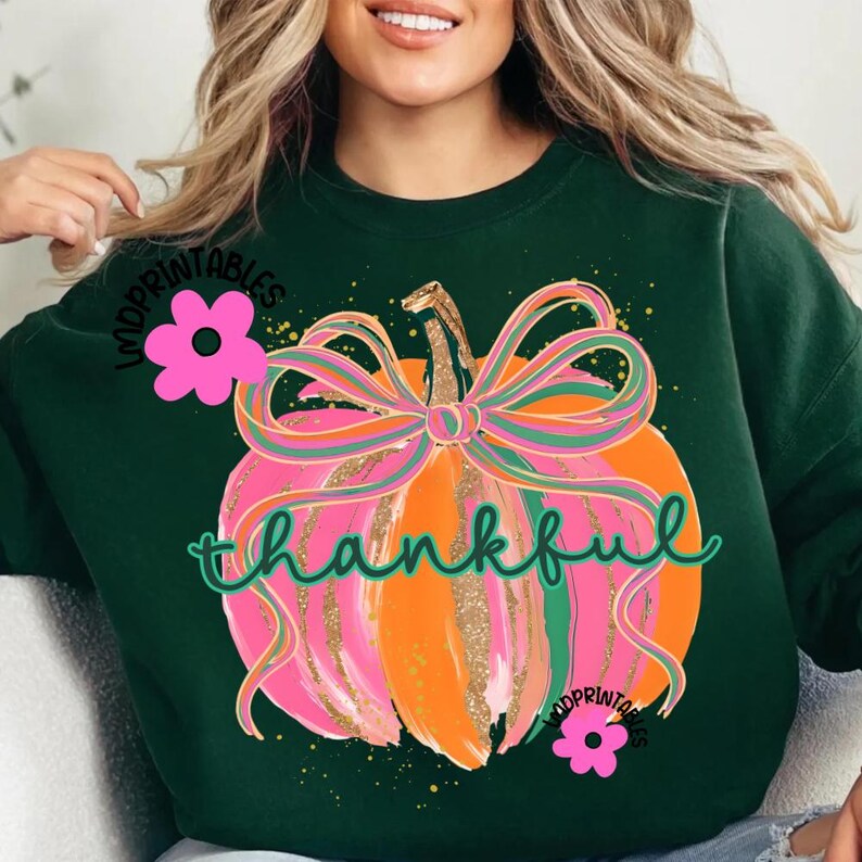 Peut inclure: Sweat-shirt vert fonc&eacute; avec un motif de citrouille color&eacute;e. La citrouille est orange et rose avec une tige et un n&oelig;ud dor&eacute;s &agrave; paillettes. Le mot "thankful" est &eacute;crit en vert. Des fleurs roses et le texte "MDPRINTABLES" sont &eacute;galement visibles.