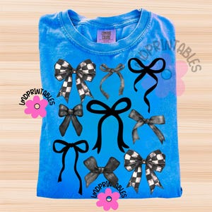 May include: A blue Comfort Colors t-shirt featuring a collection of black and white checkered and solid black bows. The bows are arranged in a pattern across the front of the shirt. The shirt has a crew neck and short sleeves.