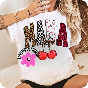 May include: White t-shirt with a colorful graphic design. The word "MAMA" is displayed in leopard print, checkered, and cherry patterns. Below, "LMDPRINTABLES" is written above a pink flower and two red cherries.