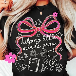 May include: Black t-shirt with a large pink and red bow design and the words "helping little minds grow." White illustrations of stars, an apple, a notebook, and other school-related items are also featured.