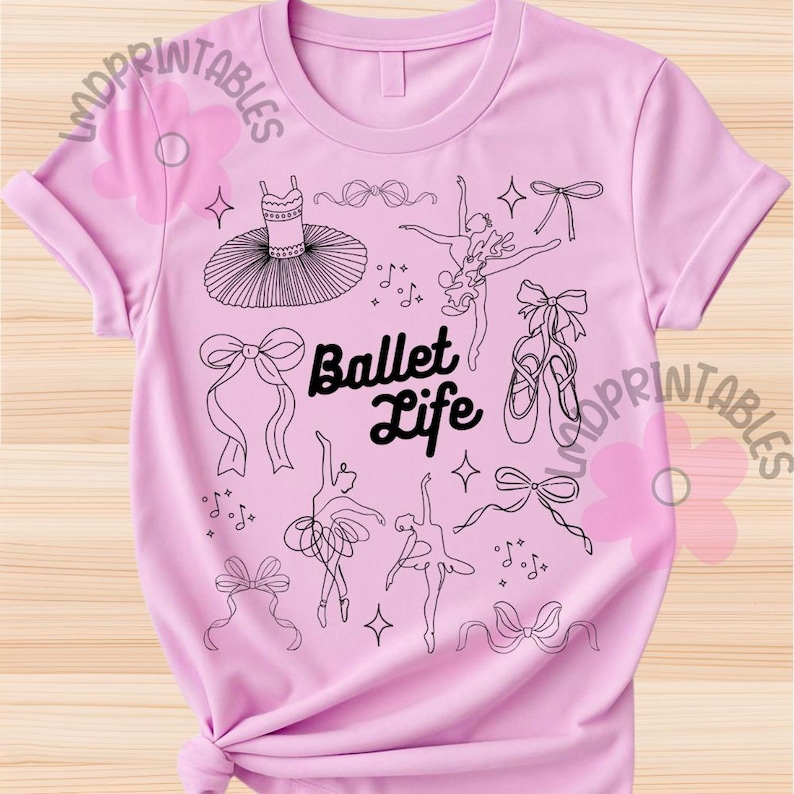 May include: A light pink t-shirt featuring a black and white illustration of ballet-themed elements. The design includes a tutu, ballet shoes, bows, dancers, and the words "Ballet Life".