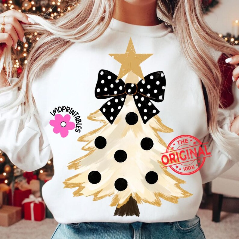 May include: White sweatshirt featuring a Christmas tree design. The tree is gold with black polka dots and a black and white polka dot bow. A gold star tops the tree. The text "LMDPRINTABLES" and "THE ORIGINAL" are also visible.