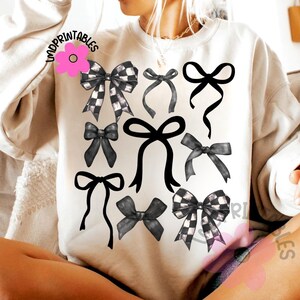 May include: Cream-colored sweatshirt featuring a collection of black and white bows in various styles. Some bows have a checkered pattern, while others are solid black. The design includes the text "IMPRINTABLES" in the upper left corner.