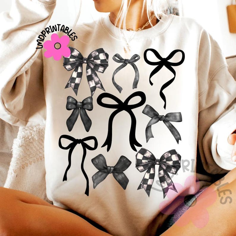 May include: Cream-colored sweatshirt featuring a collection of black and white bows in various styles. Some bows have a checkered pattern, while others are solid black. The design includes the text "IMPRINTABLES" in the upper left corner.