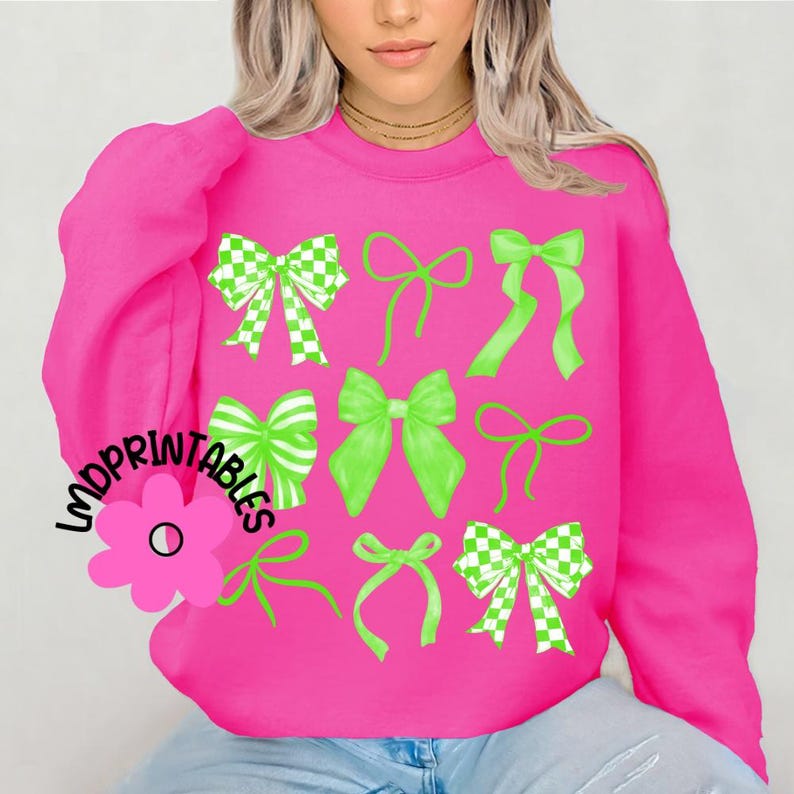 May include: A bright pink sweatshirt featuring a collection of green bows in various styles. Some bows have a checkered pattern, while others are solid green. The text "LMDPRINTABLES" is printed on the left side of the sweatshirt.