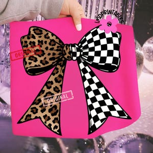 May include: A hot pink tote bag featuring a large bow design. One side of the bow has a leopard print pattern, while the other side has a black and white checkered pattern. The word "ORIGINAL" is stamped on the bag.