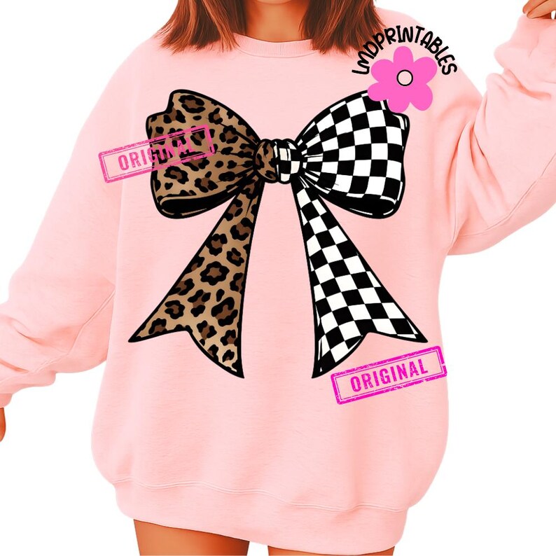 May include: Pink sweatshirt featuring a large bow design. The bow is split, with a leopard print on one side and a black and white checkered pattern on the other. The word "ORIGINAL" is stamped on the bow in pink.