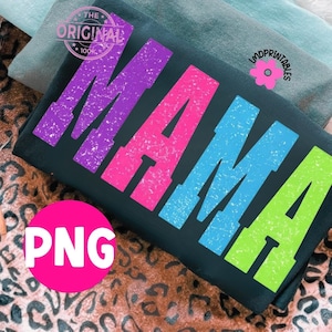 Pu&ograve; includere: T-shirt nera con la scritta "MAMA" in grandi lettere colorate e consumate: viola, rosa, blu e verde. La maglietta ha uno stile vintage e retr&ograve;. L'immagine include anche il testo "PNG" in un cerchio rosa.