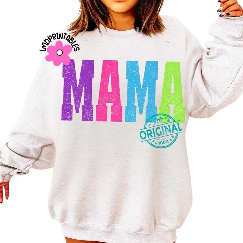 Pu&ograve; includere: Una felpa grigio chiaro con la parola "MAMA" in grandi lettere colorate: viola, rosa e verde. Sotto la parola "MAMA" c'&egrave; una grafica circolare che recita "THE ORIGINAL" e "100%" in blu.