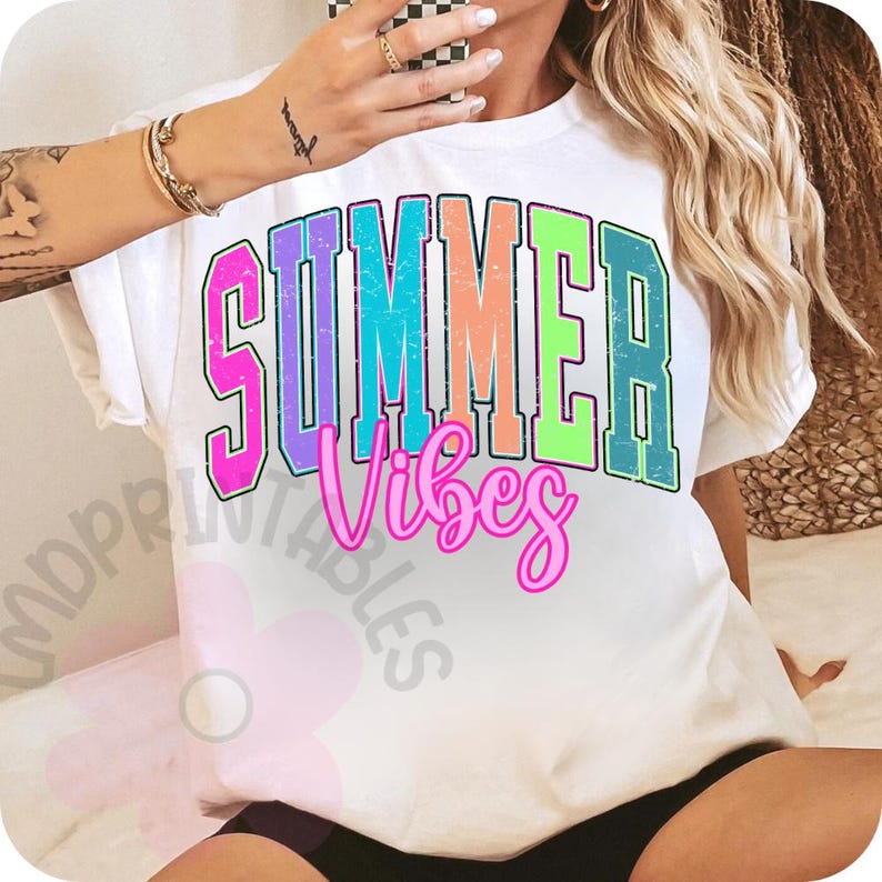 Puede incluir: Camiseta blanca con las palabras "SUMMER Vibes" en una fuente retro colorida. La palabra "SUMMER" est&aacute; en un estilo de letras de bloque con un degradado de rosa, morado, azul, naranja y verde. "Vibes" est&aacute; en cursiva rosa.