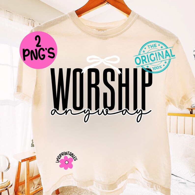 May include: A cream-coloured t-shirt with the words "WORSHIP anyway" in black script. A white bow graphic is above the word "WORSHIP". The shirt has a "The Original" stamp and a pink circle with "2 PNG'S" on it.