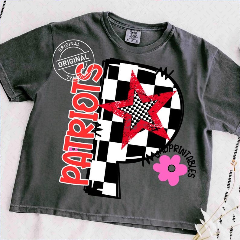 K&ouml;nnte beinhalten: Dunkelgraues T-Shirt mit einem grafischen Design. Das Design zeigt einen roten Stern &uuml;ber einem schwarz-wei&szlig; karierten Kreis, das Wort "PATRIOTS" in Rot und eine rosa Blume. Das Shirt tr&auml;gt auch den Text "ORIGINAL" und "WAD PRINTABLES".