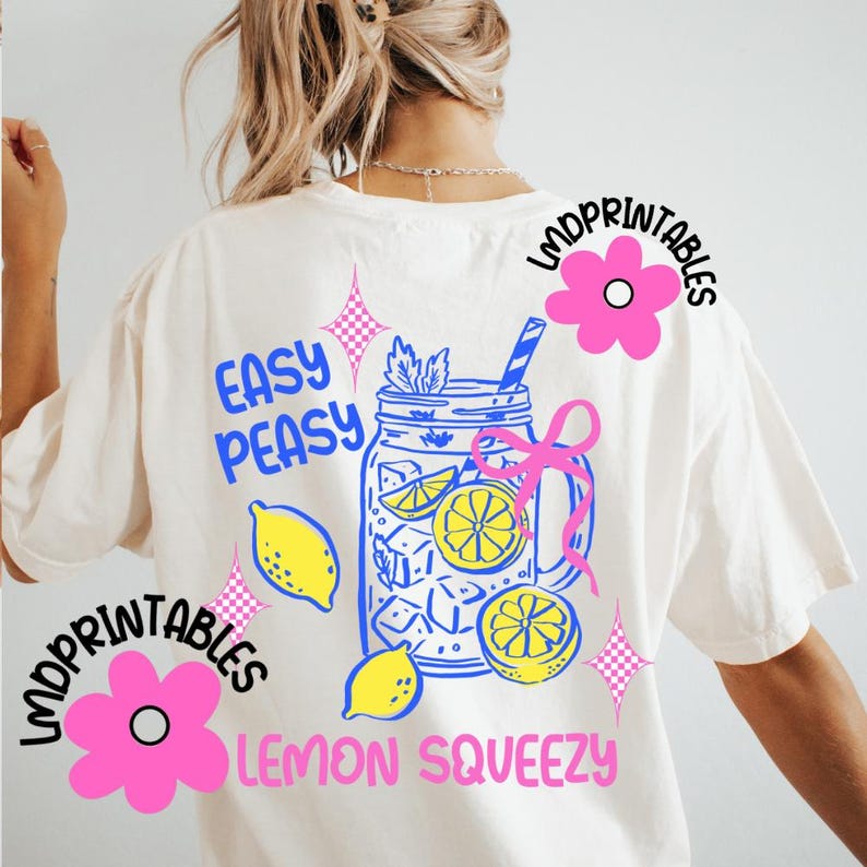 May include: Cream-coloured t-shirt with a colourful graphic design. The design features a mason jar filled with lemons and ice, with the words "Easy Peasy Lemon Squeezy". Pink flowers and text are also included.