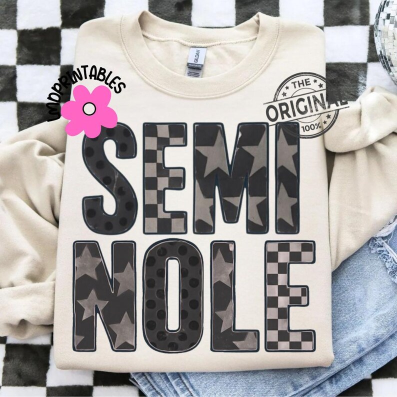 May include: Cream-colored sweatshirt with the word "SEMINOLE" in large, bold letters. The letters are black with patterns of stars, polka dots, and checkered designs. The text "THE ORIGINAL 100%" is printed on the upper right side.