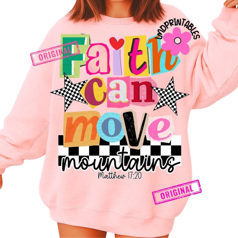 May include: A light pink sweatshirt with the words "Faith can move mountains" in colorful, layered text. The design includes a heart, stars, and a flower. The text "Matthew 17:20" is also included.
