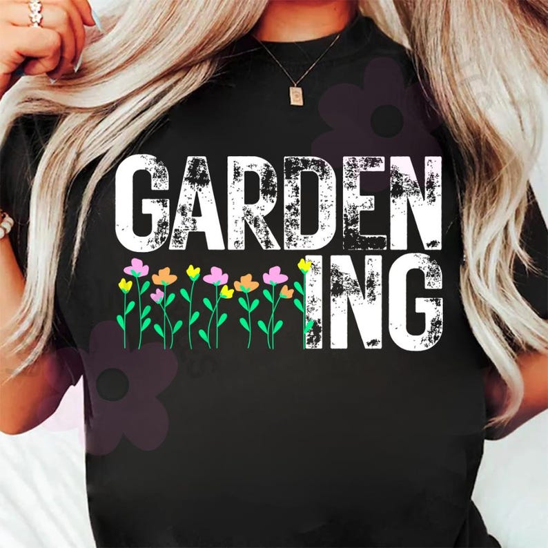 May include: Black t-shirt with the word "GARDENING" in distressed white letters. Below the word "ING" are colorful flowers with green stems. The shirt is a crew neck.
