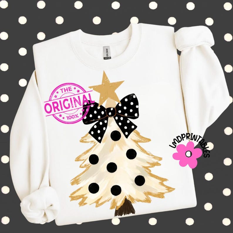 May include: White sweatshirt featuring a Christmas tree design. The tree is gold with black polka dots and a black and white polka dot bow. The text "THE ORIGINAL 100%" is stamped on the shirt.