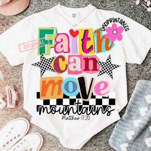 May include: White t-shirt with a colorful graphic design. The design features the words "Faith can move mountains" in various bright colors and fonts, along with two checkered stars and a pink flower. The text "Matthew 17:20" is also included.