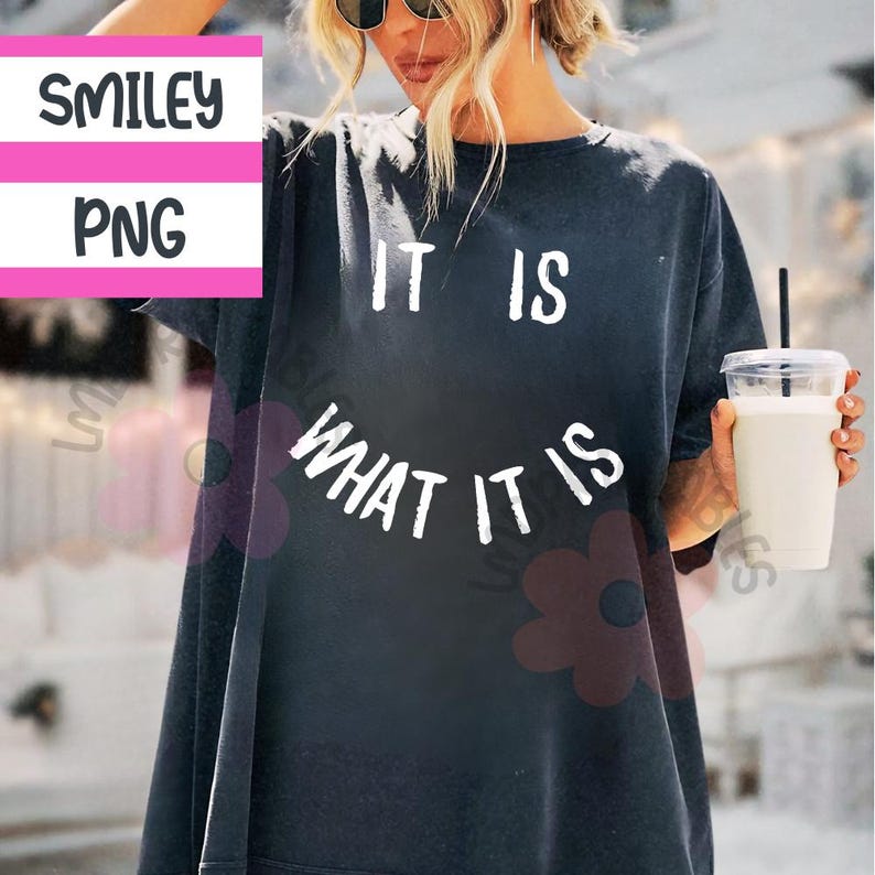 May include: Dark gray t-shirt with the text "IT IS WHAT IT IS" in white. The text is arranged in a curved smiley face design. The shirt has short sleeves and a relaxed fit.