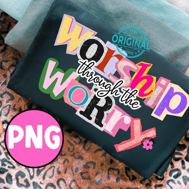 May include: Dark green t-shirt with the text "Worship through the Worry" in a colorful, collage-style design. The word "PNG" is in a pink circle in the lower left corner. The shirt is folded on top of a leopard print fabric.
