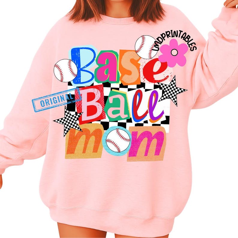 以下が含まれることがあります： 明るいピンク色のスウェットシャツ。カラフルなブロックレターで「Base Ball Mom」と書かれています。デザインには野球ボール、花、市松模様の星が含まれています。「ORIGINAL」の文字が左側にスタンプされています。