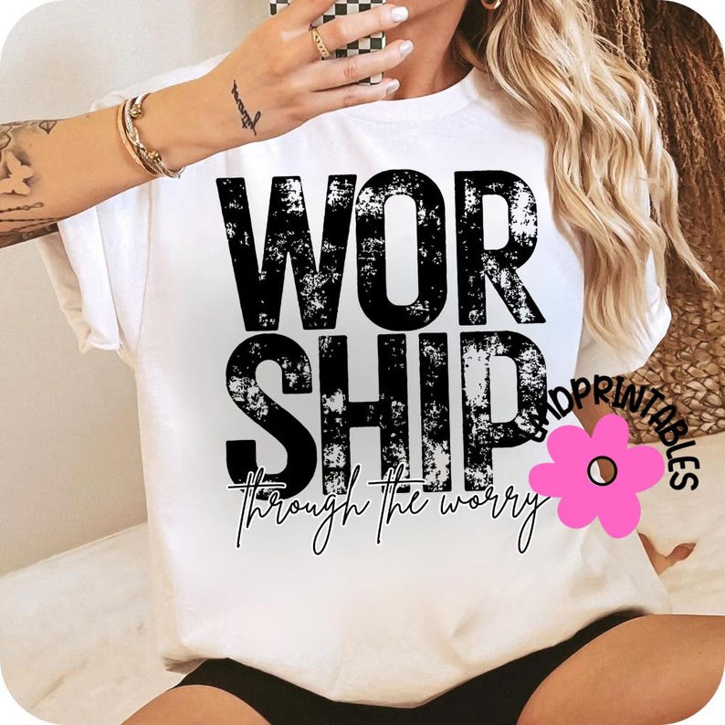 Pu&ograve; includere: T-shirt bianca con la parola "WORSHIP" in grandi lettere nere sbiadite. Sotto, la parola "SHIP" &egrave; stampata, e sotto, la frase "through the worry" &egrave; scritta in corsivo. Un fiore rosa &egrave; nell'angolo in basso a destra.
