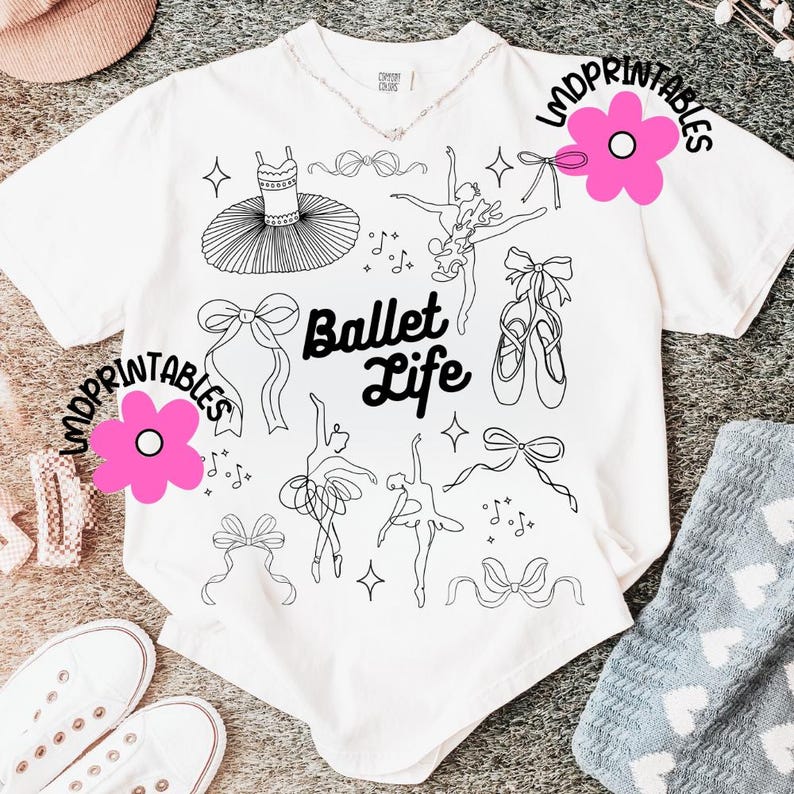 May include: White t-shirt with a black line art design featuring ballet-themed illustrations. The design includes a tutu, ballet shoes, bows, and dancers. The words "Ballet Life" are also printed on the shirt.
