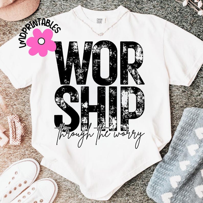 Pu&ograve; includere: T-shirt bianca con la parola "WORSHIP" in grandi lettere nere sbiadite. Sotto, la frase "through the worry" &egrave; scritta in corsivo. Fa parte di una collezione di abbigliamento.