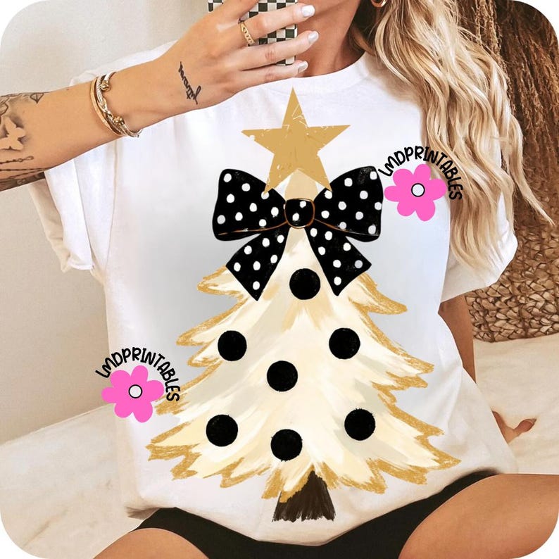 May include: White t-shirt featuring a Christmas tree design. The tree is gold with black polka dots and a black and white polka dot bow. A gold star sits atop the tree. The text "LMDPRINTABLES" is on the shirt.
