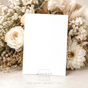 Pu&ograve; includere: Un biglietto bianco vuoto con un sottile motivo a rombi, appoggiato a un bouquet di fiori secchi ed erba della pampa. I fiori sono nelle tonalit&agrave; del crema, beige e marrone, creando un'estetica neutra ed elegante. Il biglietto &egrave; pronto per un testo personalizzato.