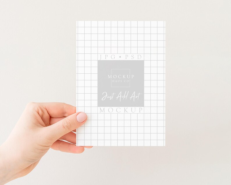 Peut inclure: Une main tenant une carte blanche avec un motif quadrill&eacute;. La carte pr&eacute;sente le texte "JPG &bull; PSD" et "Mockup Days Co" avec "Just Add Art" dans un rectangle gris. Le fond est de couleur blanc cass&eacute;.