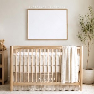 May include: A nursery interior with a wooden cot, cream bedding, and a blanket. A framed blank print hangs above the cot. A teddy bear sits on a wooden side table next to a lamp. A potted plant adds greenery. The room has a neutral colour palette, creating a calm atmosphere.
