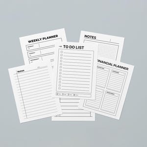 May include: A selection of white paper sheets featuring black text, such as a weekly planner, to-do list, notes, and a financial planner. The sheets are displayed against a light grey backdrop. The planner pages are designed for organization.