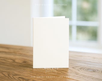 Maqueta de tarjeta de felicitación, tarjeta blanca plegada vertical en blanco con estilo sobre un escritorio de madera, plantilla PSD de objeto inteligente fácil de usar, JPG y PNG.
