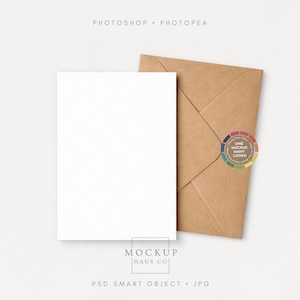 May include: A blank white card and a brown envelope are displayed on a light background. The card is rectangular and positioned vertically. The envelope is folded and has a circular sticker with the text "ONE MOCKUP MANY LOOKS". The image includes the text "MOCKUP HAUS CO".