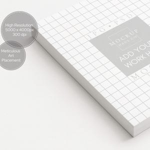 Peut inclure: Un bloc-notes blanc avec un motif quadrill&eacute;, avec le texte "ADD YOUR WORK HERE" et "MOCKUP HAUS CO." Le texte suppl&eacute;mentaire comprend "High Resolution 5000 x 4000px 300 dpi" et "Meticulous Art Placement."