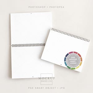 May include: Two white spiral-bound calendars, one vertical and one horizontal, featuring a circular colour wheel graphic with the text "ONE MOCKUP, MANY LOOKS!" and "PHOTOSHOP • PHOTOPEA" and "MOCKUP HAUS CO" and "PSD SMART OBJECT • JPG" printed.
