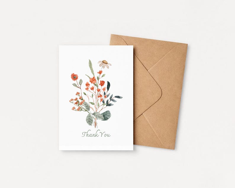 May include: A white greeting card with a watercolor floral design featuring orange and green foliage. The card reads "Thank You" in a script font. A brown envelope is next to the card.