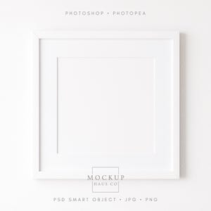 May include: A square white picture frame with a white mat. The frame is centered on a white background. The text at the top reads "PHOTOSHOP • PHOTOPAE". The text at the bottom reads "PSD SMART OBJECT • JPG • PNG". The logo "MOCKUP HAUS CO" is at the bottom.