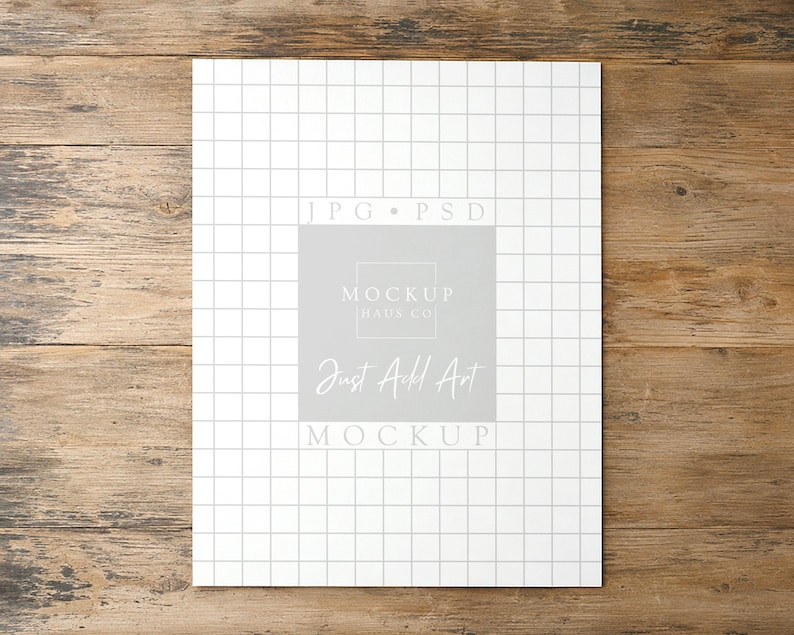 May include: A rectangular white paper sheet featuring a thin black grid pattern. Centered on the sheet is a light gray square containing the text JPG PSD, MOCKUP HAUS CO, Just Add Art, and MOCKUP in white and light gray lettering.