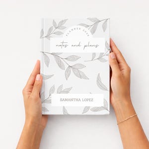 K&ouml;nnte beinhalten: Ein wei&szlig;er Planer mit floralem Design und dem Text "Planner 2020" und "notes and plans". Der Planer wird von zwei H&auml;nden gehalten. Der Name "Samantha Lopez" ist unten auf dem Planer aufgedruckt.