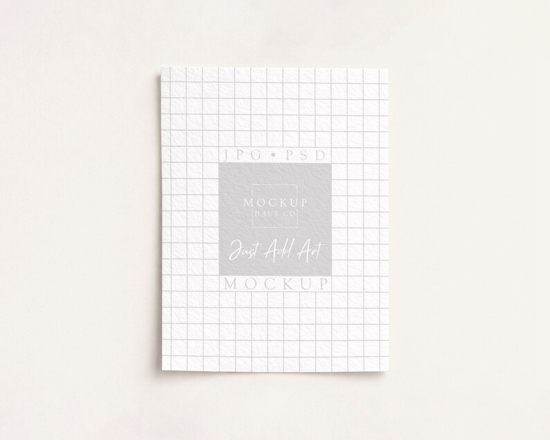 May include: A white notebook with a grid pattern, featuring the text "Just Add Art" in a soft, elegant font. The notebook is centered on a light background, creating a clean and minimalist aesthetic.