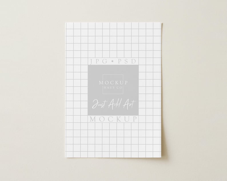 May include: A white paper with a grid pattern and the text "JPG PSD" at the top. A gray square in the center contains the text "MOCKUP HAUS CO" and "Just Add Art MOCKUP" in a handwritten style font.