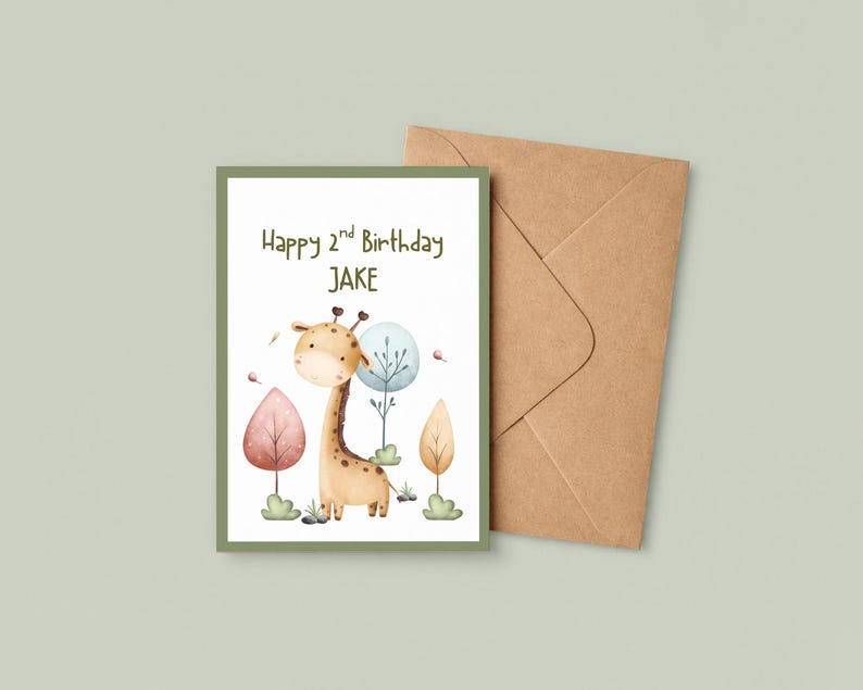 May include: A birthday card with a watercolor illustration of a giraffe and the text "Happy 2nd Birthday JAKE". The card has a green border and is accompanied by a brown envelope. The giraffe is tan with brown spots.