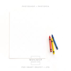 Puede incluir: Una hoja de papel blanca con tres crayones: rojo, amarillo y azul. Los crayones están colocados en diagonal en el lado derecho. El texto "PHOTOSHOP • PHOTOPEA" está en la parte superior y "MOCKUP HAUS CO" en la inferior.