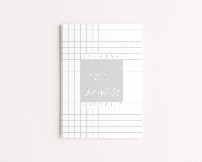 May include: A white notebook with a grid pattern and the text "JPG &bull; PSD" at the top. The center features a gray square with the text "MOCKUP HAUS CO." and "Just Add Art MOCKUP" in a handwritten font.