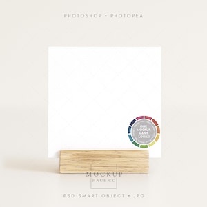May include: A white square card is held by a light brown wooden block. The words "PHOTOSHOP • PHOTOPEA" are at the top. A color wheel with the text "ONE MOCKUP MANY LOOKS!" is on the right. The bottom text reads "MOCKUP HAUS CO" and "PSD SMART OBJECT • JPG".