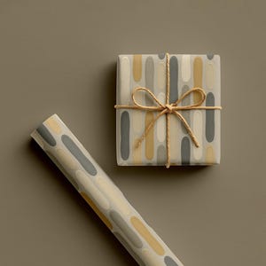 May include: A wrapped gift box and a roll of wrapping paper. The gift box is wrapped in paper with a pattern of vertical ovals in grey, yellow, and cream. The box is tied with twine. The roll of paper has the same pattern.