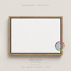 Może przedstawiać: Prostokątne płótno z białą powierzchnią, oprawione w jasnobrązową drewnianą ramę. Obraz zawiera tekst "PHOTOSHOP • PHOTOPAE" na górze i "MOCKUP HAUS CO" na dole. Koło kolorów znajduje się w rogu.